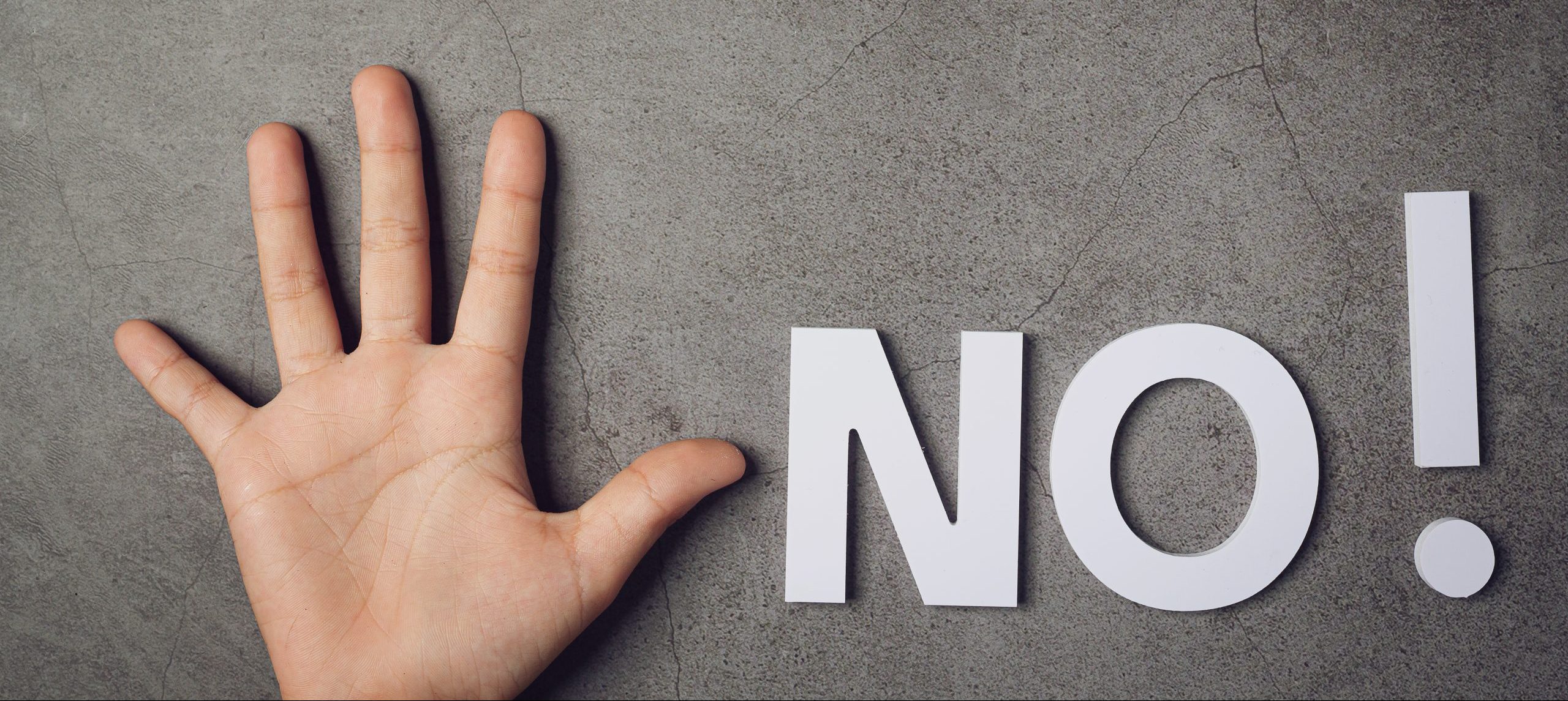 word "NO" with child's hand on dark background